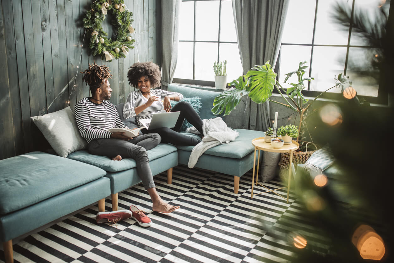 couple sitting on their couch surrounded by seasonal greenery 