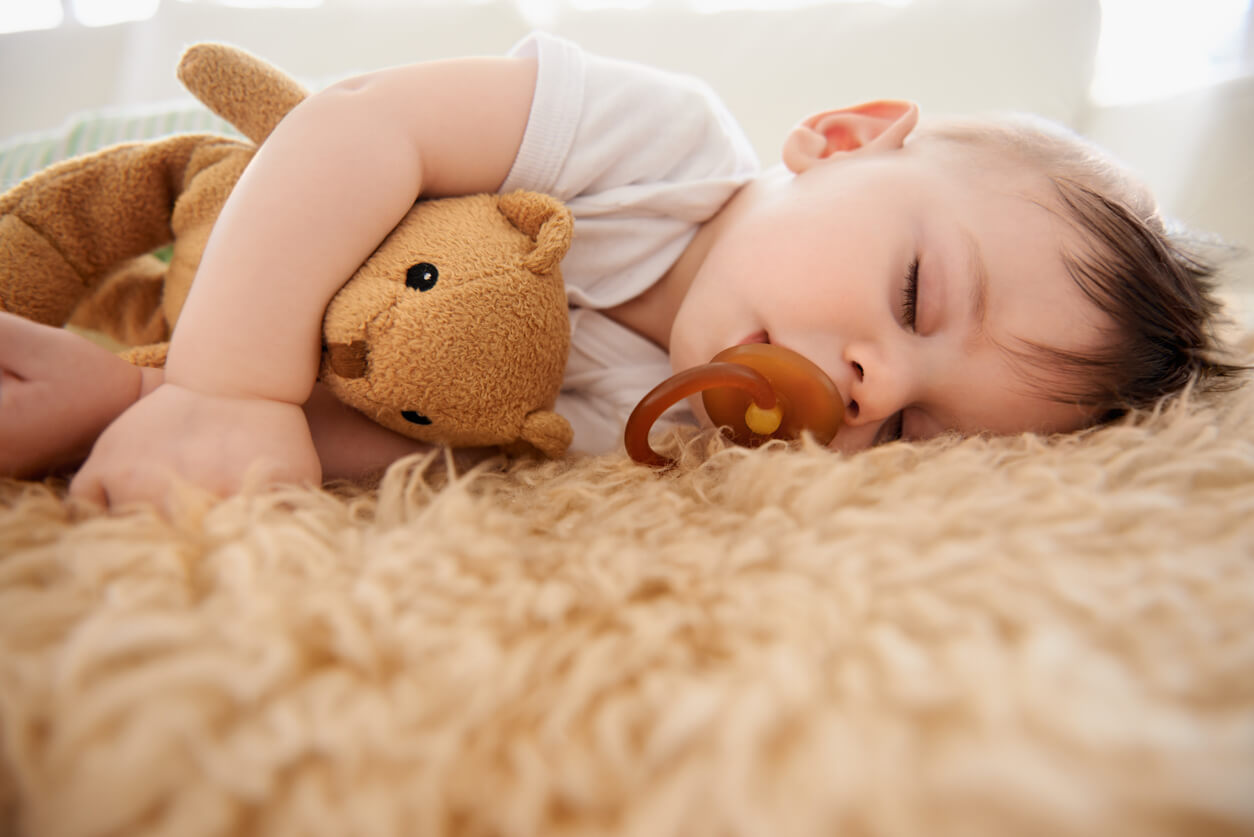 Baby napping on cozy carpet with teddy bear